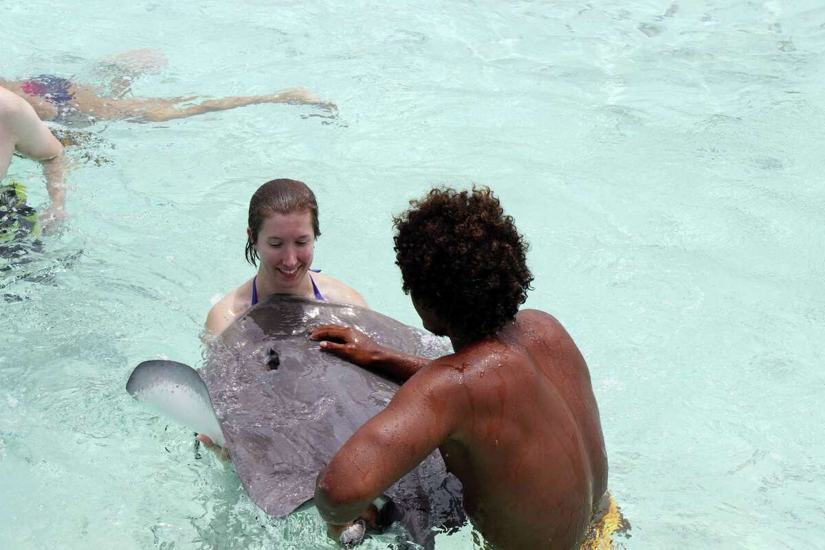 In this Nov. 2, 2015 photo courtesy of Jennifer McDermott, Associated Press writer Jennifer McDermott holds an older, docile stingray with help from a tour guide in Bora Bora. Bora Bora offers celebrity-style seclusion and has been a vacation destination for the likes of Justin Bieber, Jennifer Aniston and Usain Bolt. It's located 160 miles from Tahiti with a balmy and relatively consistent temperature of 80 degrees Fahrenheit. (Courtesy of Jennifer McDermott via AP)