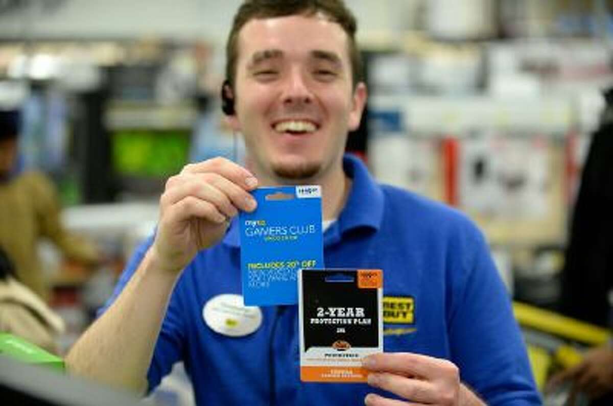 Best Buy employee Christopher Gervais, right, shows the electronics retailer's protection plan and game club cards.