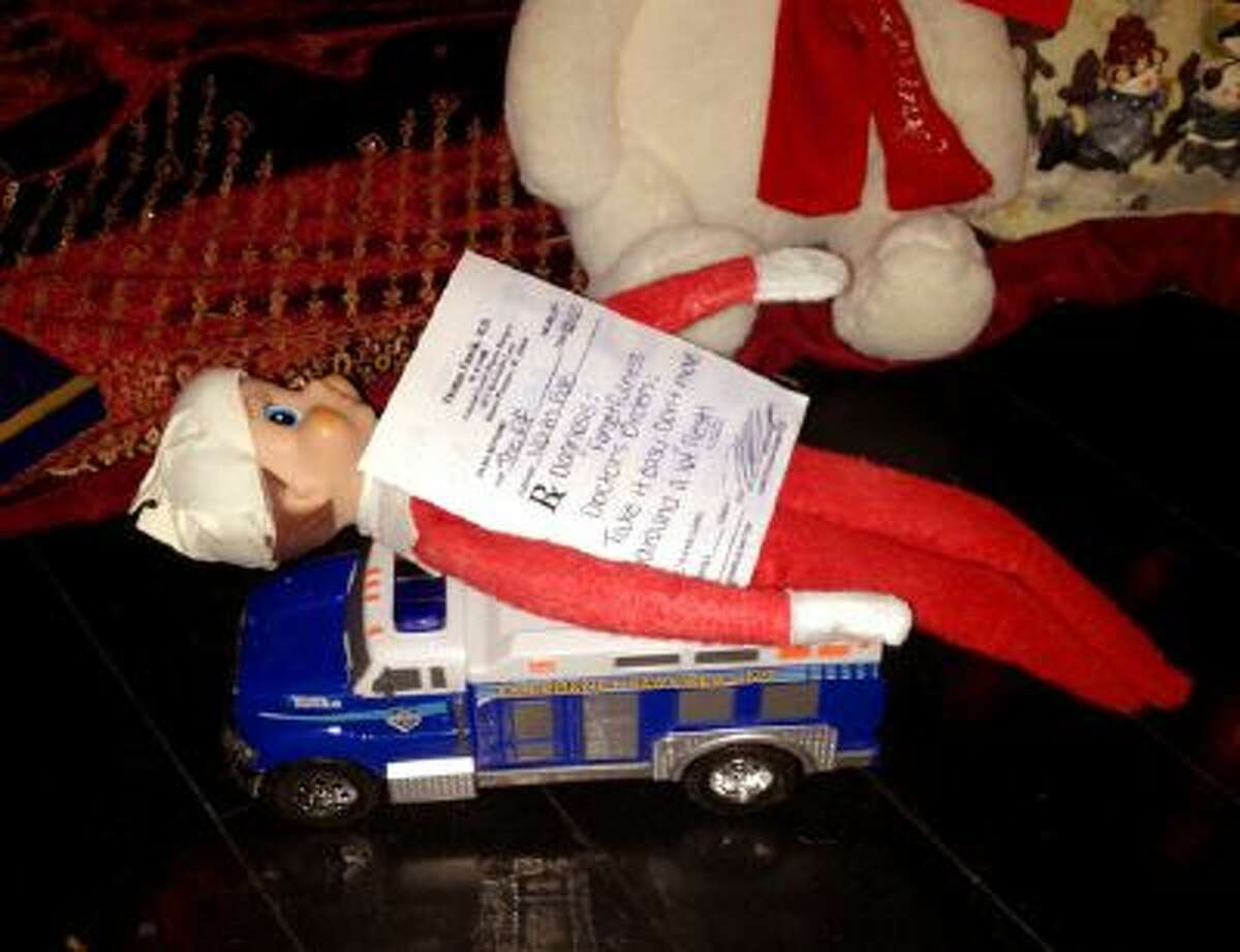 This Dec 11, 2013 photo released by Kim Boerman shows a bandaged elf from the Elf on the Shelf with a prescription by the Christmas tree in the Boerman home in Charleston, S.C. Boerman procured a doctor's prescription after the elf fell from the chandelier during dinner.