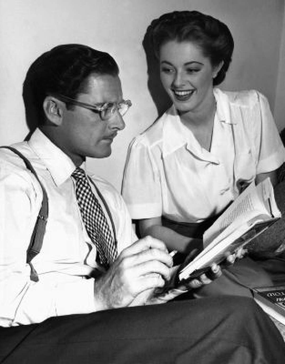 In this Aug. 25, 1945 photo, Errol Flynn seems to be in a literary mood as, between takes on the set of "Never Say Goodbye," he reads an amusing passage from a new novel to his leading lady, Eleanor Parker, who appears to enjoy the presentation in Los Angeles.