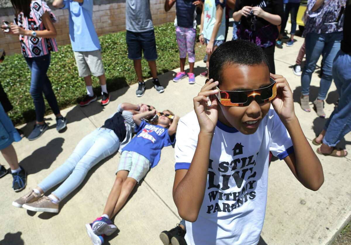 Kevin Brown, right, adjusts his special solar glasses as teachers and students at Virginia Allred Stacey Junior-Senior High School at Lackland AFB, witness the eclipse.