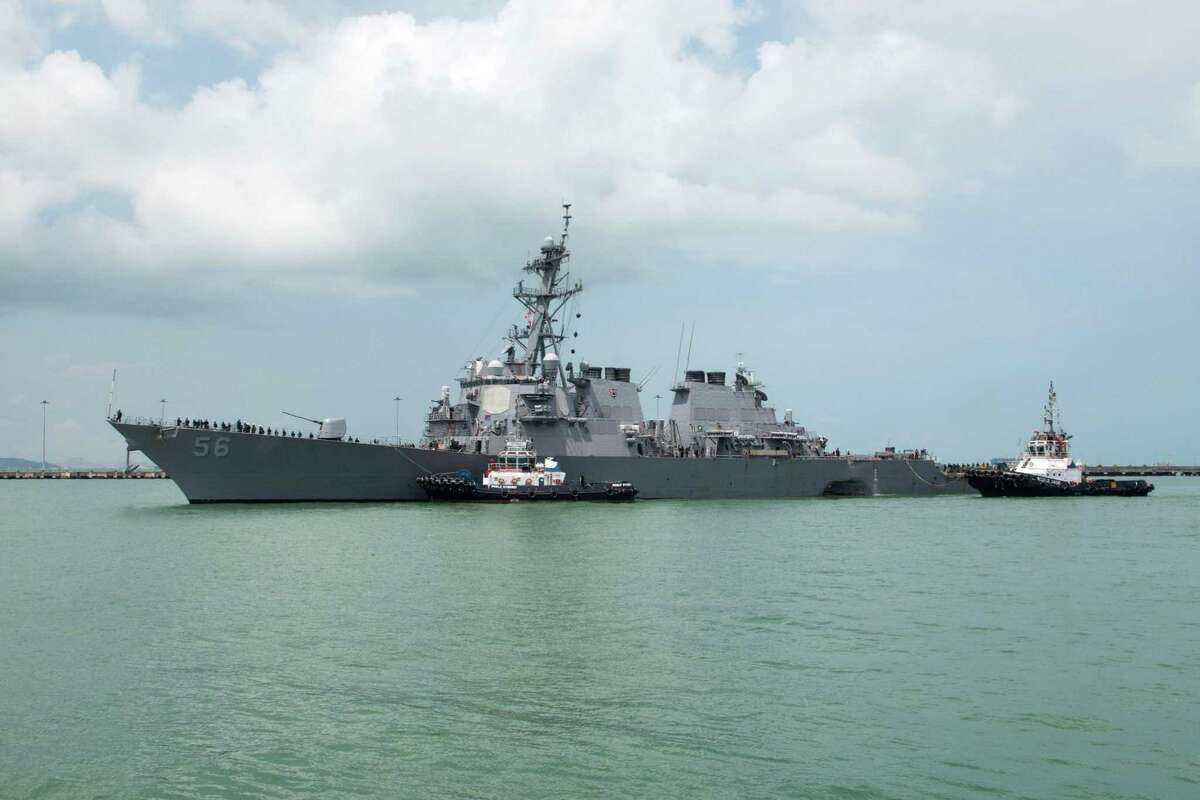 In a photo provided by the U.S. Navy, the USS John S. McCain, a U.S. guided-missile destroyer, is seen with a hole in its rear left side as tugboats guide it toward Changi Naval Base in Singapore.