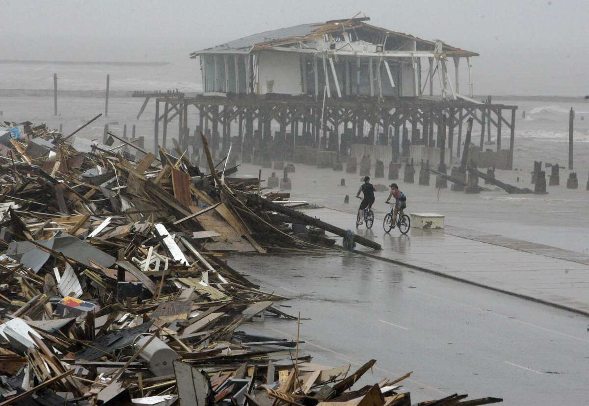 FILE - In this Sept. 14, 2008, file photo, cyclists ride past debris piled up on the seawall road after Hurricane Ike hit the Texas coast in Galveston. (AP Photo/Matt Slocum, File)