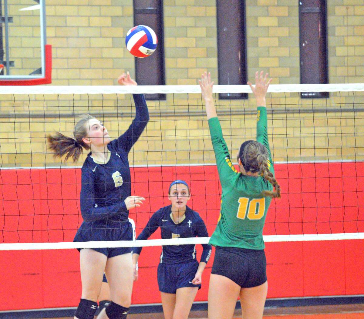 Father McGivney junior Emma Deist, left, goes up for a kill during Tuesday’s match against Piasa Southwestern at the Roxana Tournament.