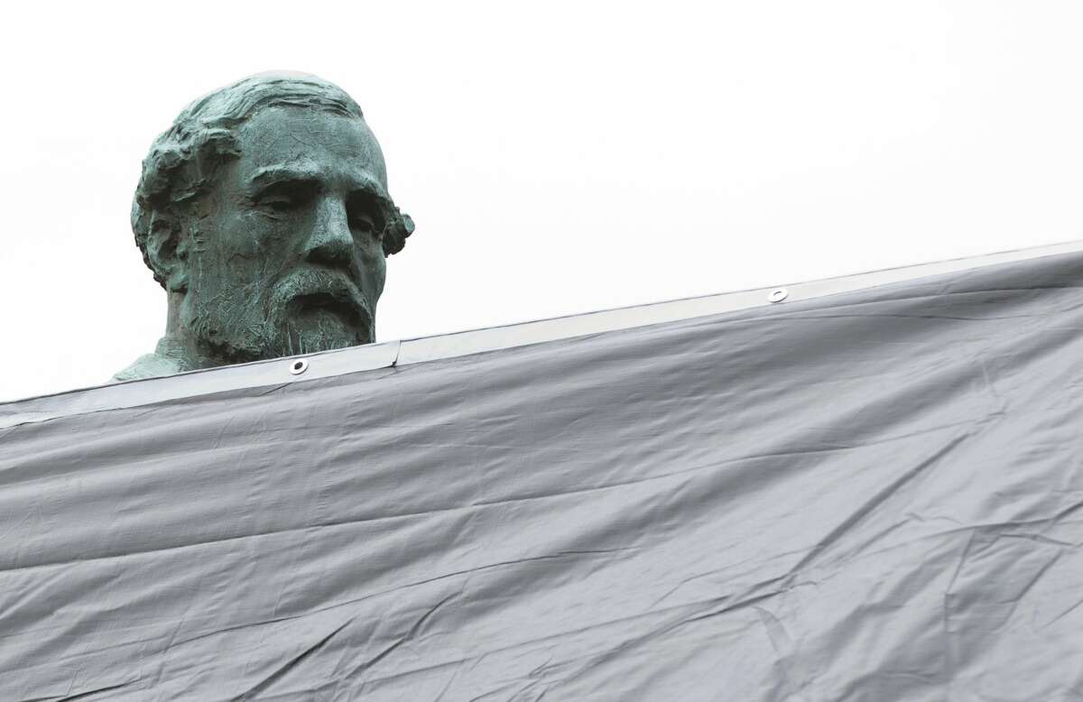 City workers drape a tarp over the statue of Confederate General Robert E. Lee in Emancipation park in Charlottesville, Va., Wednesday, Aug. 23, 2017.  (AP Photo/Steve Helber)
