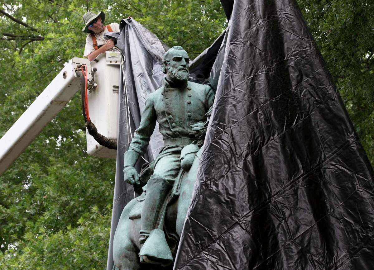 City workers drop a tarp over the statue of Confederate General Stonewall Jackson in Justice park in Charlottesville, Va., on Wednesday﻿. Some residents cheered as the statue was covered, but later one man began cutting the tarp.
