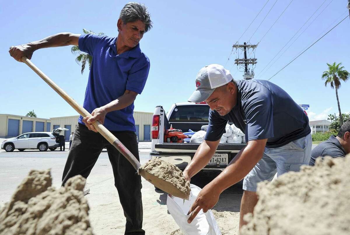 Leo Sermiento, left, and Emilio Gutierrez, right, fill sandbags in preparation of a tropical system on Wednesday, Aug. 23, 2017, on South Padre Island, Texas. Texas Gov. Greg Abbott has ordered the State Operations Center to elevate its readiness level and is making state resources available for preparation and possible rescue and recovery actions amid forecasts a tropical storm will make landfall along the Texas Gulf Coast. (Jason Hoekema/The Brownsville Herald via AP)