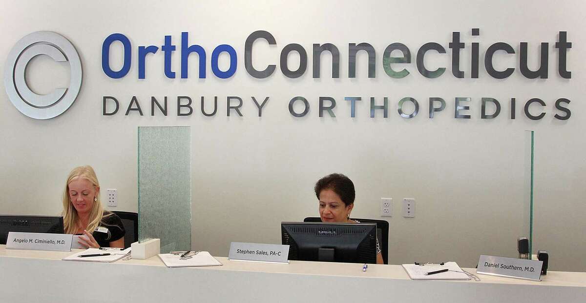Melissa Ferrari and Carmen Torres work at the front desk at OrthoConnecticut in Danbury, Conn., on Wednesday, Aug. 23, 2017.