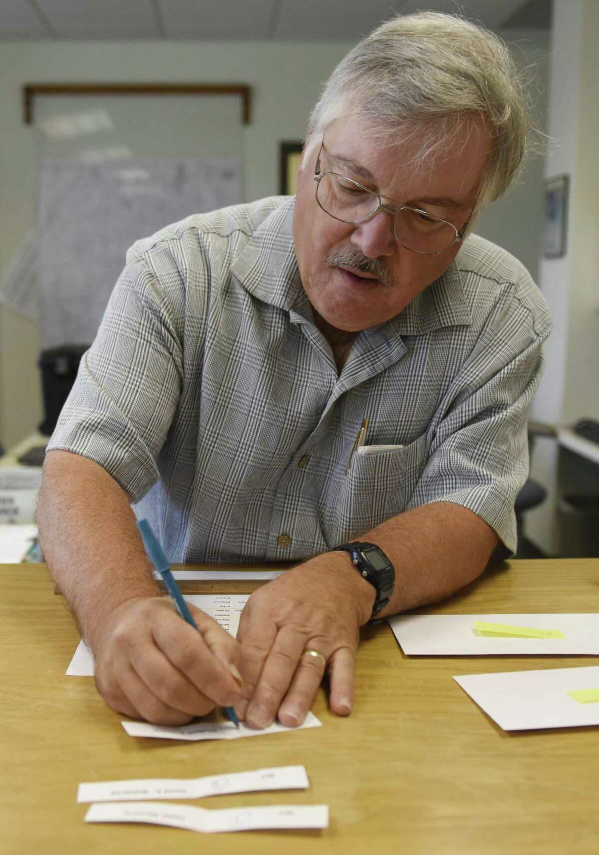 Democratic Registrar of Voters Mike Aurelia writes a candidate's names after drawing it from a tin during the Registrar of Voters ballot order lottery at Town Hall in Greenwich, Conn. Thursday, Aug. 24, 2017. The names of candidates were put into a biscotti tin and drawn blindly to determine the order in which they would be put on the election ballot.