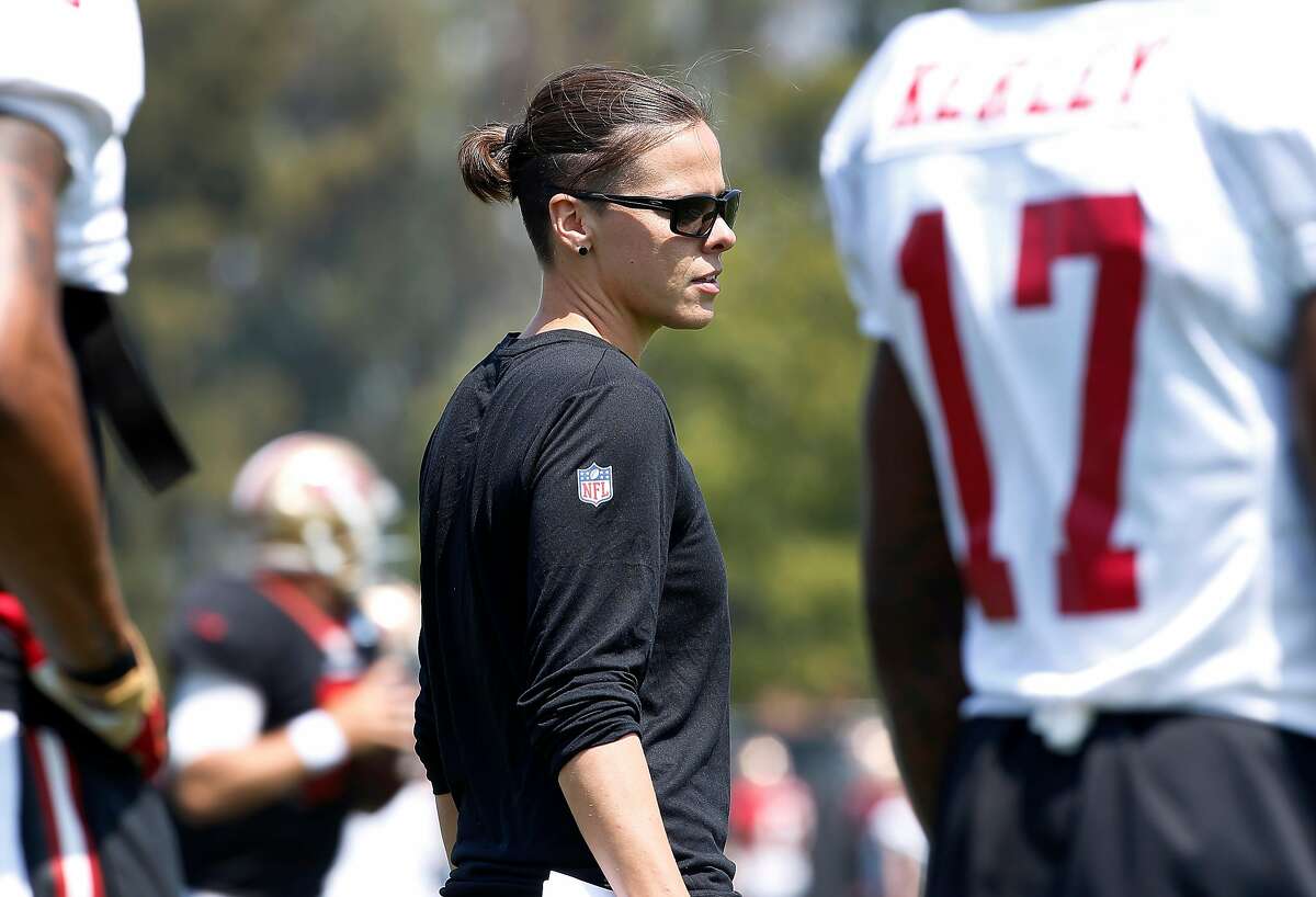 San Francisco 49ers assistant coach Katie Sowers players run through drills during practice at the San Francisco 49ers training facility on Wednesday, August 23, 2017, in Santa Clara, California. Sowers, 31, made more history, becoming the NFL's first openly gay coach. San Francisco 49ers officially hired Katie Sowers for the 2017 season last week, making her the team's first female assistant coach.