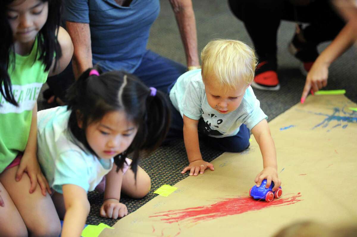 Two-year-old Cooper Anderson, of Stamford, rolls a car through some paint during the final Messy Thursdays! art class inside the Harry Bennett branch of the Ferguson Library in Stamford, Conn. on Thursday, August 24, 2017.