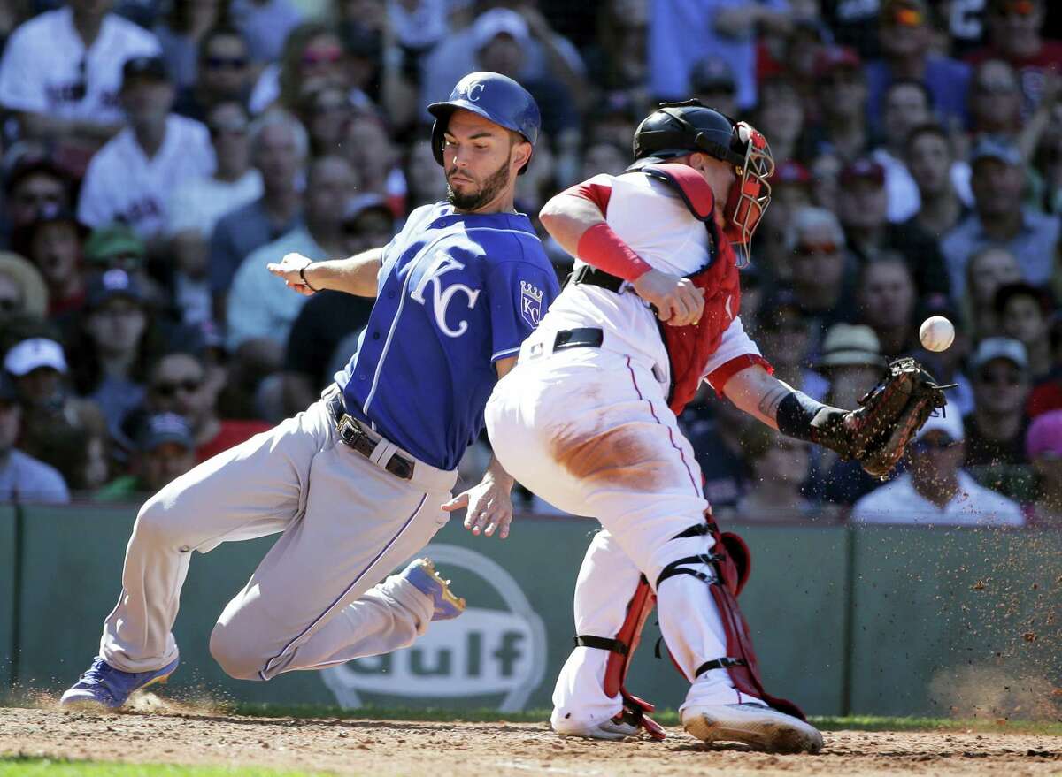 The Royals’ Eric Hosmer, left, scores as Red Sox catcher Christian Vazquez tries to get his glove on the ball in the eighth inning Sunday in Boston.