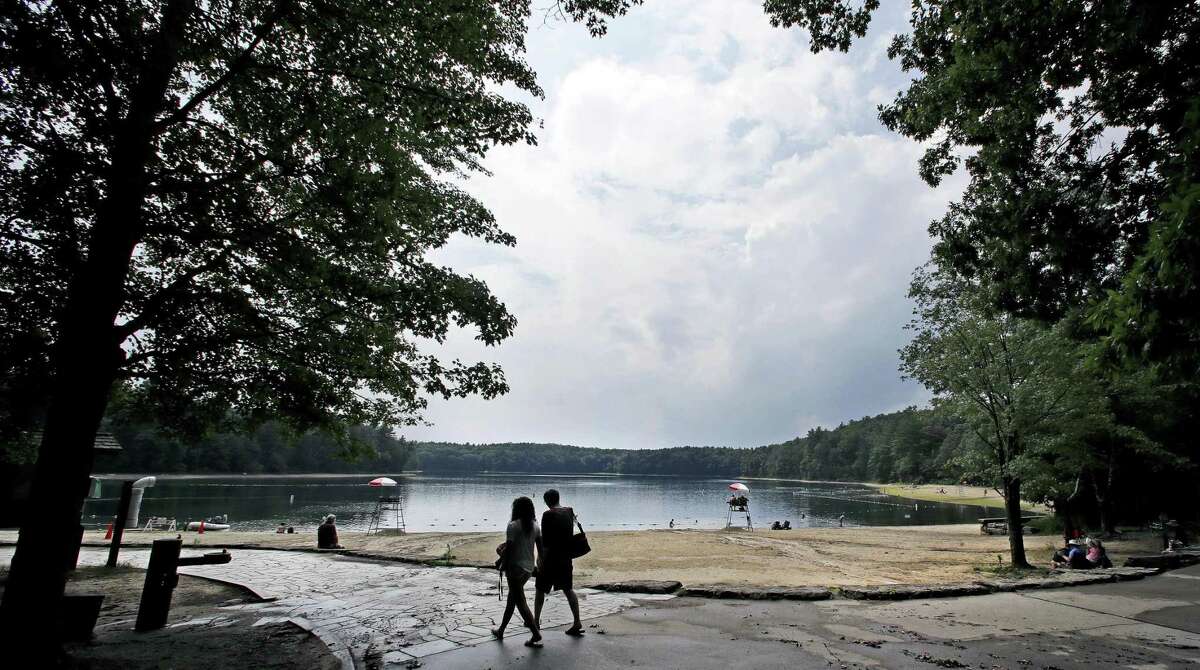 A couple walks along the shore of Walden Pond in Concord, Mass. Two centuries after Thoreau's birth, people are still following in Thoreau's footsteps to discover Walden Pond, the little lake he immortalized, and its picturesque and historic environs.