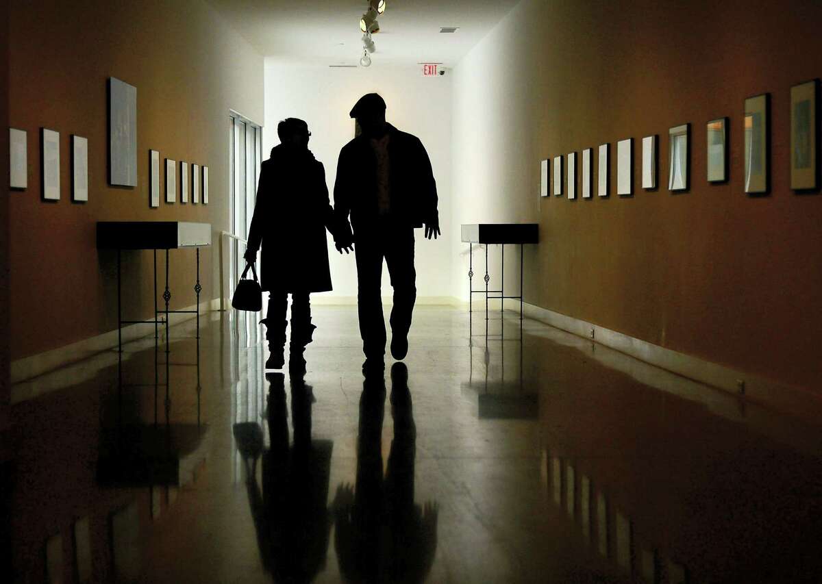 A couple walks down the Bacon Gallery at the Erie Art Museum, in Erie, Pa.
