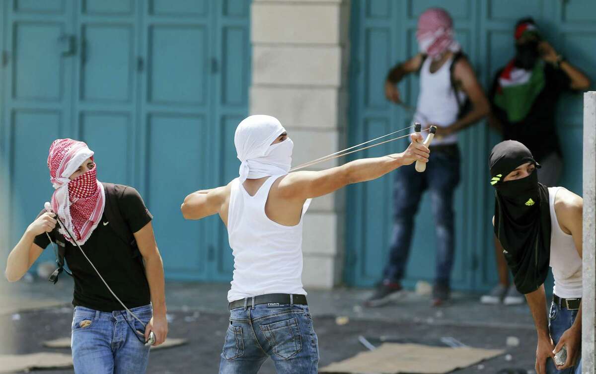 A Palestinian uses a slingshot against Israeli soldiers during clashes in the West Bank city of Bethlehem, Friday, July 21, 2017. Israel police severely restricted Muslim access to a contested shrine in Jerusalem’s Old City on Friday to prevent protests over the installation of metal detectors at the holy site.
