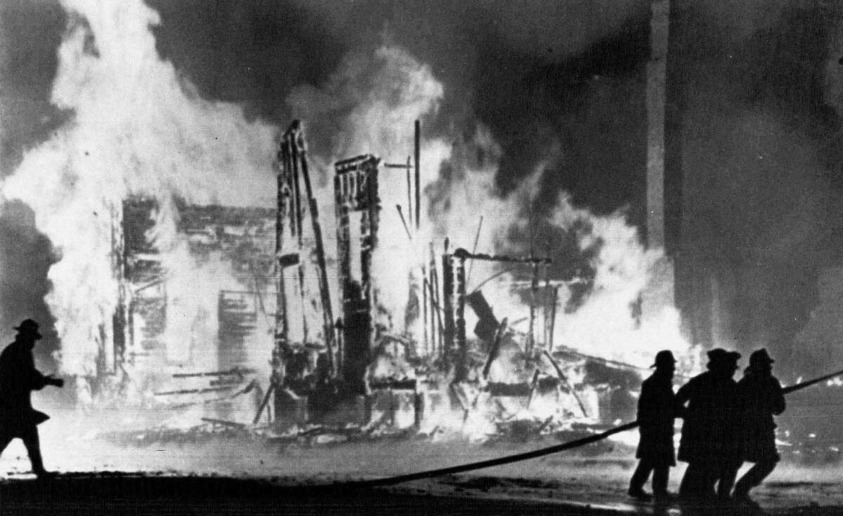 FILE - In this July 25, 1967 file photo, firefighters try to control blazing buildings after riots in Detroit. Hundreds of fires were reported in the city. Five days of violence would leave 33 blacks and 10 whites dead, and more than 1,400 buildings burned. More than 7,000 people were arrested. (AP Photo/File)