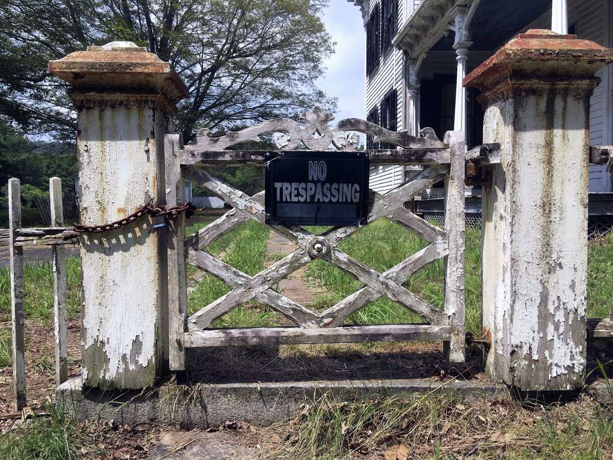 In this July 12 photo, a sign declares no trespassing allowed in an abandoned house on the grounds of a long-abandoned, 62-acre village in East Haddam.