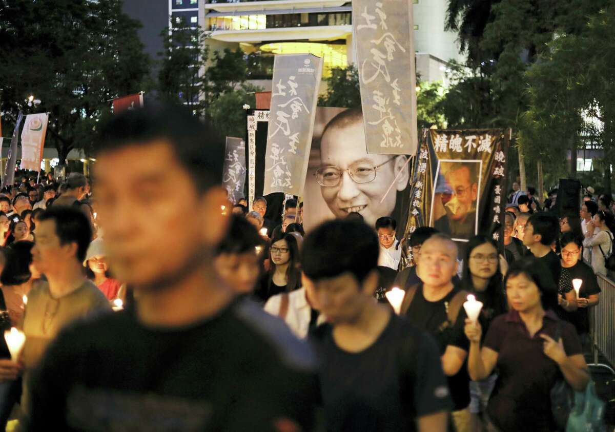 Protesters carry photos of late Chinese Nobel Peace laureate Liu Xiaobo as they march on a street to mourn him in Hong Kong, Saturday, July 15, 2017. China cremated the body of the imprisoned Nobel Peace Prize laureate who died earlier in the week after a battle with cancer amid international criticism of Beijing for not letting him travel abroad as he had wished.