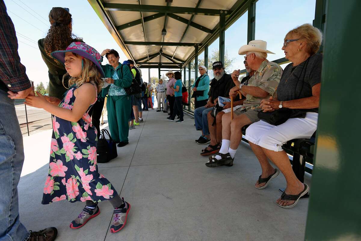 Ellie Higgins, 5, left, holding Tom Higgins' hand while train passengers wait for the arrival of the first SMART train departing from the Sonoma County Airport station Friday at 12:49 p.m. in Santa Rosa, California. Rides are free today. August 25, 2017.