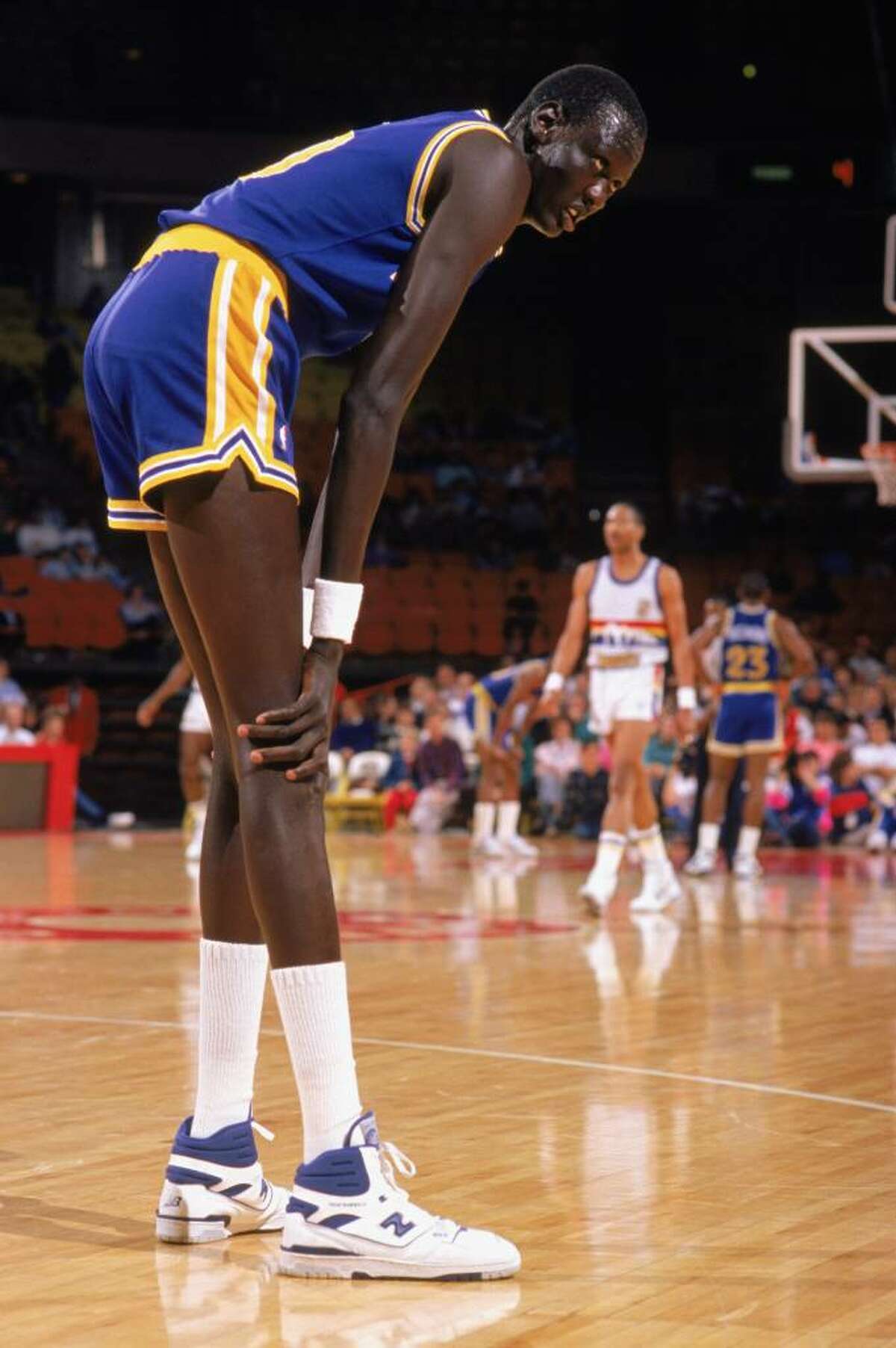 1988: Manute Bol #10 of the Golden State Warriors rests on the court during an NBA game in the 1988-89 season. NOTE TO USER: User expressly acknowledges and agrees that, by downloading and/or using this Photograph, User is consenting to the terms and conditions of the Getty Images License Agreement. (Photo by: Tim DeFrisco/Getty Images