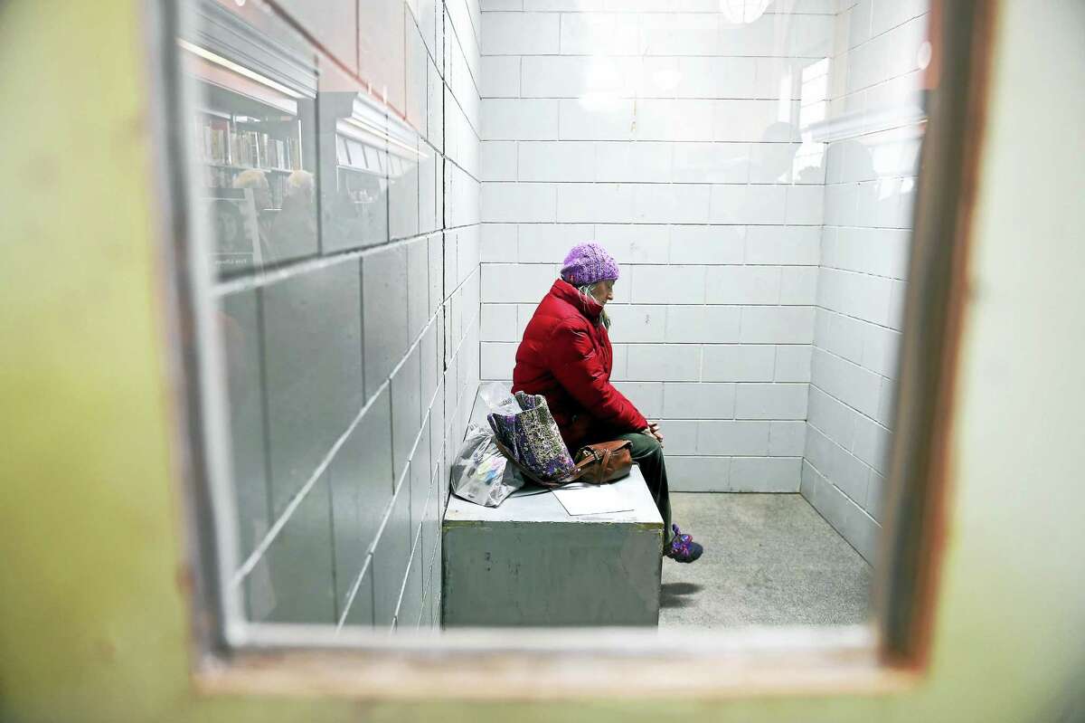Anne Burns of New Haven sits inside a replica solitary confinement cell set up inside the New Haven Free Public Library Monday.