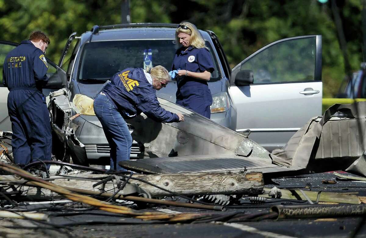 In this file photo, investigators look at the remains of a small plane along Main Street in East Hartford, Conn. Police say the student pilot of the small plane, which crashed on Oct. 11, near the Connecticut headquarters of a military jet engine manufacturer, fought with his instructor and probably crashed deliberately. East Hartford police reports disclosed Tuesday support media stories from months ago.