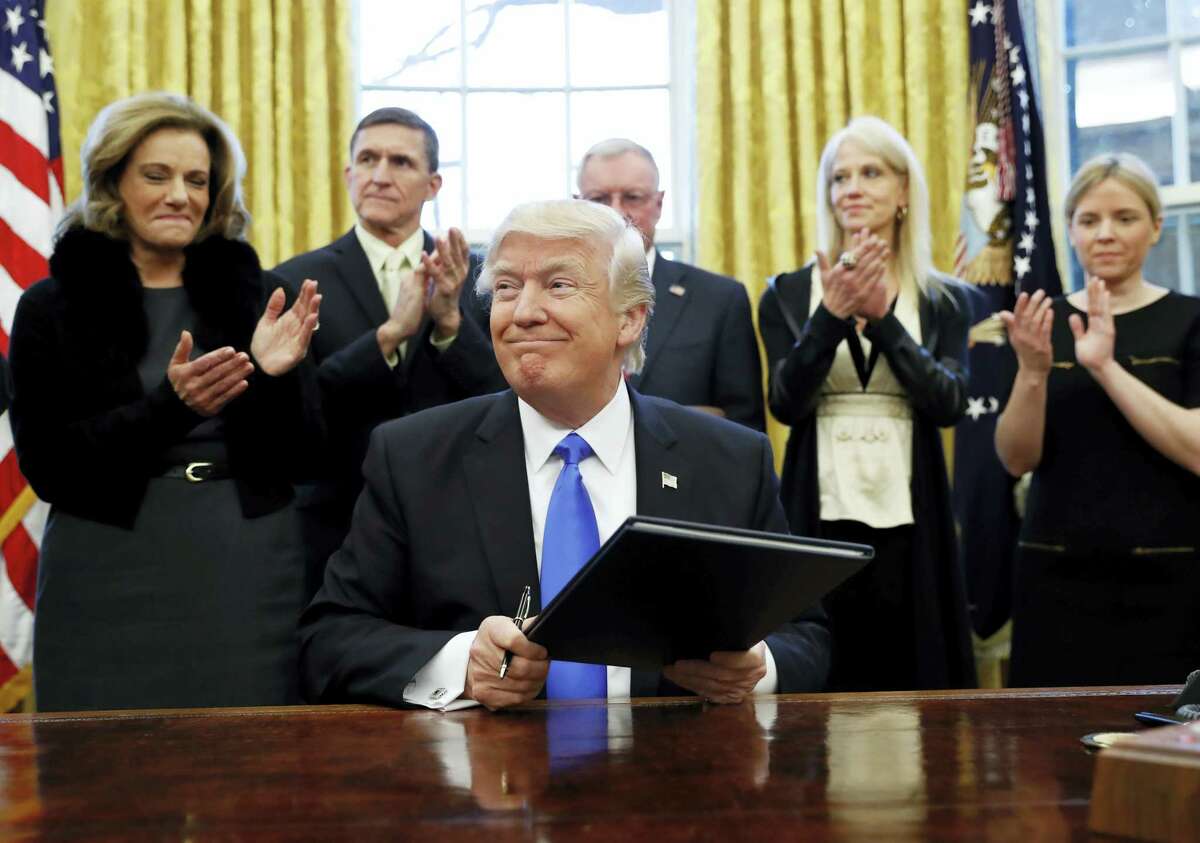 President Donald Trump smiles after signing an executive action in the Oval Office, Saturday in Washington.