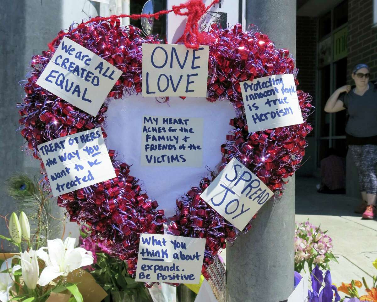 A heart-shaped wreath covered with positive messages hangs on a traffic light pole at a memorial for two bystanders who were stabbed to death Friday, while trying to stop a man who was yelling anti-Muslim slurs and acting aggressively toward two young women, including one wearing a Muslim head covering, on a light-trail train in Portland, Ore, Saturday, May 27, 2017. A memorial grew all day Saturday outside the transit center in Portland, as people stopped with flowers, candles, signs and painted rocks. Jeremy Joseph Christian, 35, was booked on suspicion of murder and attempted murder in the attack. (AP Photo/Gillian Flaccus)