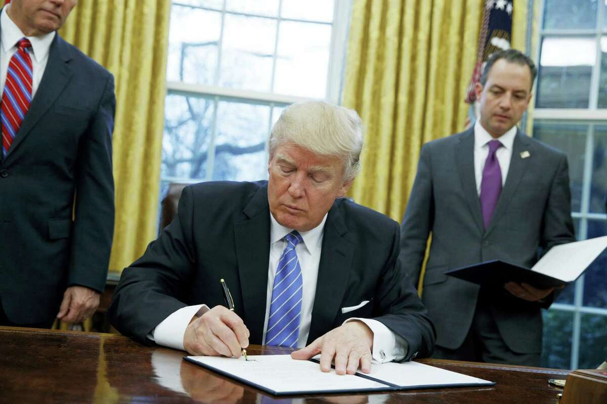 President Donald Trump signs an executive order to withdraw the U.S. from the 12-nation Trans-Pacific Partnership trade pact agreed to under the Obama administration in the Oval Office of the White House in Washington.