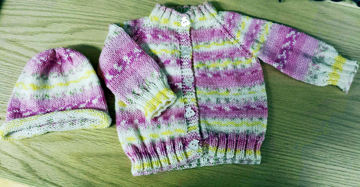 A charming baby sweater and matching hat, created by Kathy Botass.