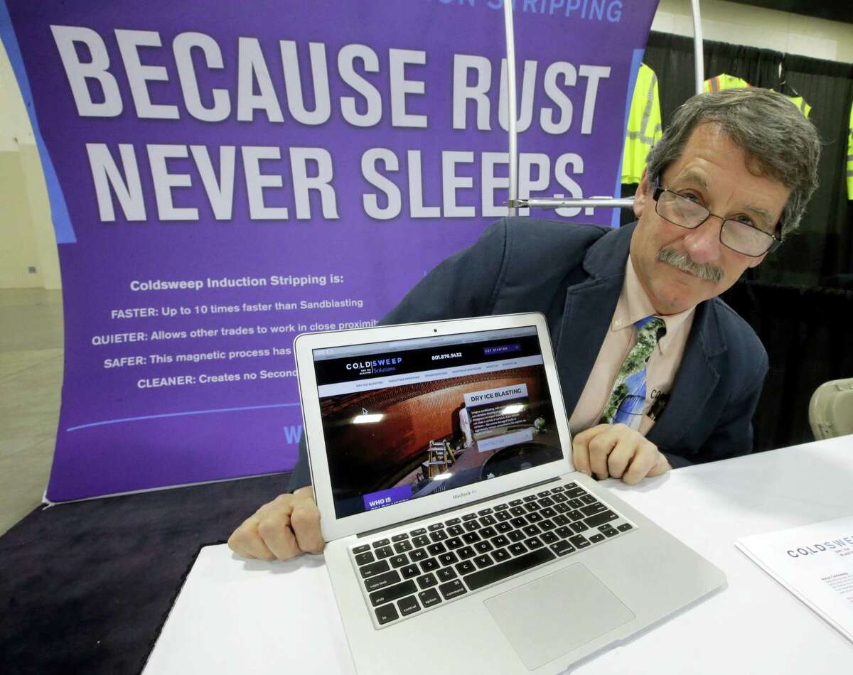 In this Feb. 28, 2017, photo, Randell Heath poses next to a laptop displaying his company’s website, in Sandy, Utah. Heath’s sandblasting company, near Salt Lake City, had its website hacked and turned into a store selling Viagra and Cialis.