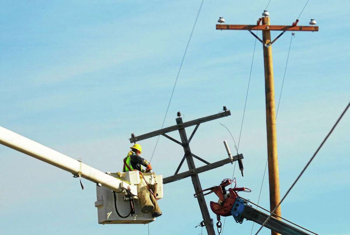 A worker moves utility wires from a damaged poles in this file photo.
