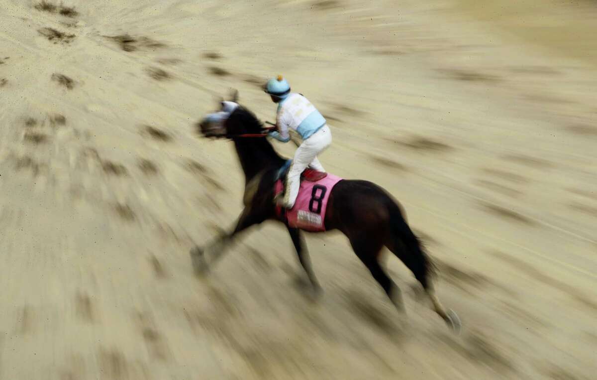 A horse runs in the mud after a race before the 143rd running of the Kentucky Derby horse race at Churchill Downs Saturday, May 6, 2017, in Louisville, Ky.