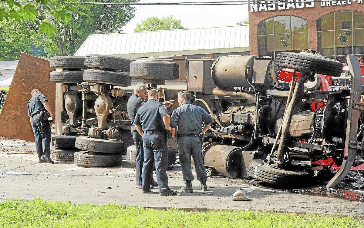Police inspect an overturned dump truck that collided with a bus causing a chain reaction at the foot of Avon Mountain on Route 44 in Avon on July 29, 2005. Several people died and many were hospitalized in the multi-vehicle crash.