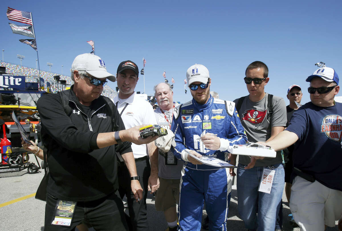 Dale Earnhardt Jr., center, signs autographs for fans at a practice session at Daytona International Speedway on Friday.