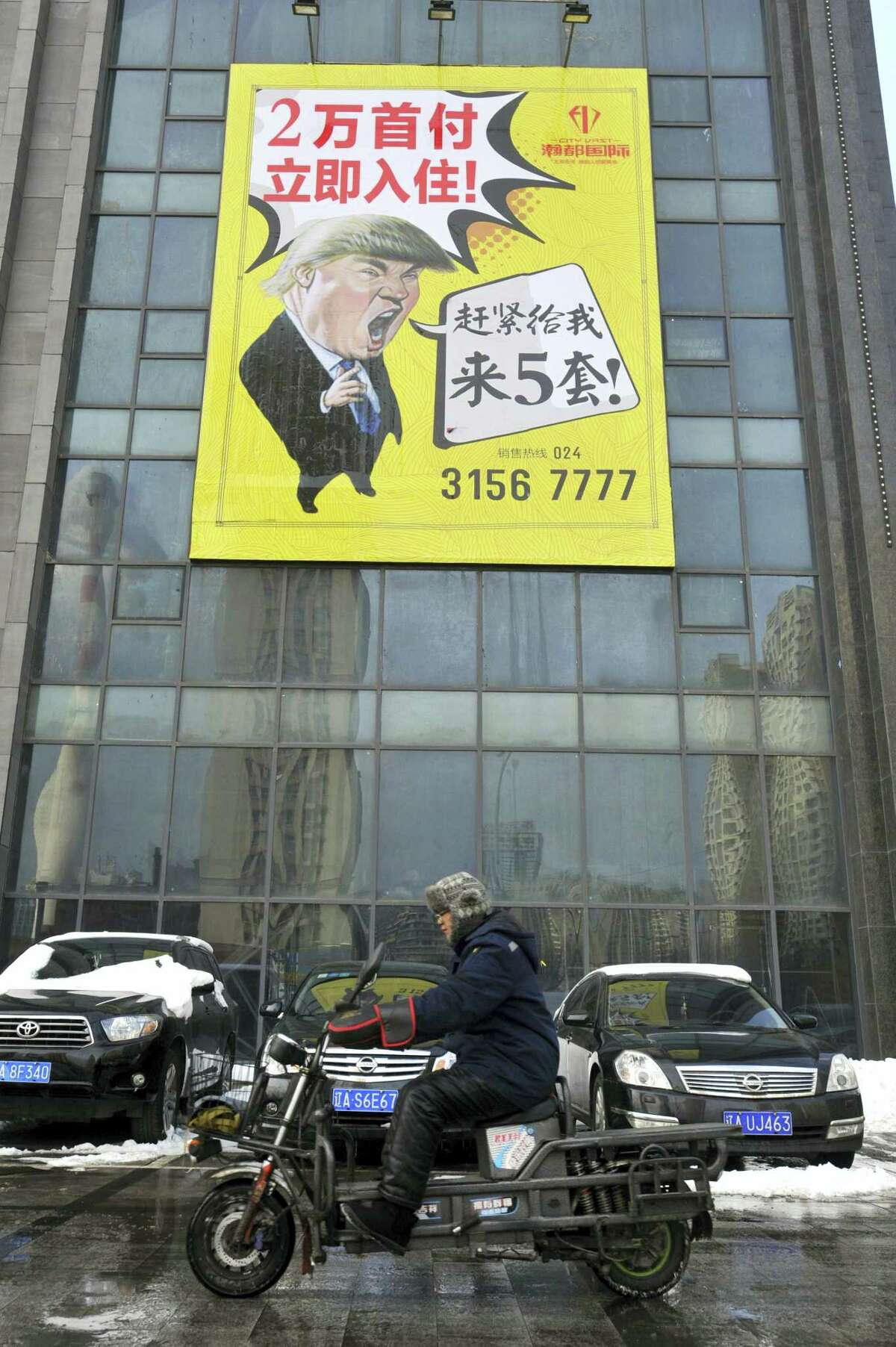 A motorcyclist drives past a real estate advertisement featuring a cartoon figure resembling U.S. President Donald Trump in Shenyang in northeastern China’s Liaoning province Wednesday, Feb. 22, 2017. After years of legal wrangling, China’s government awarded Trump’s business valuable rights to his own name last week, in the form of a 10-year trademark for construction services.