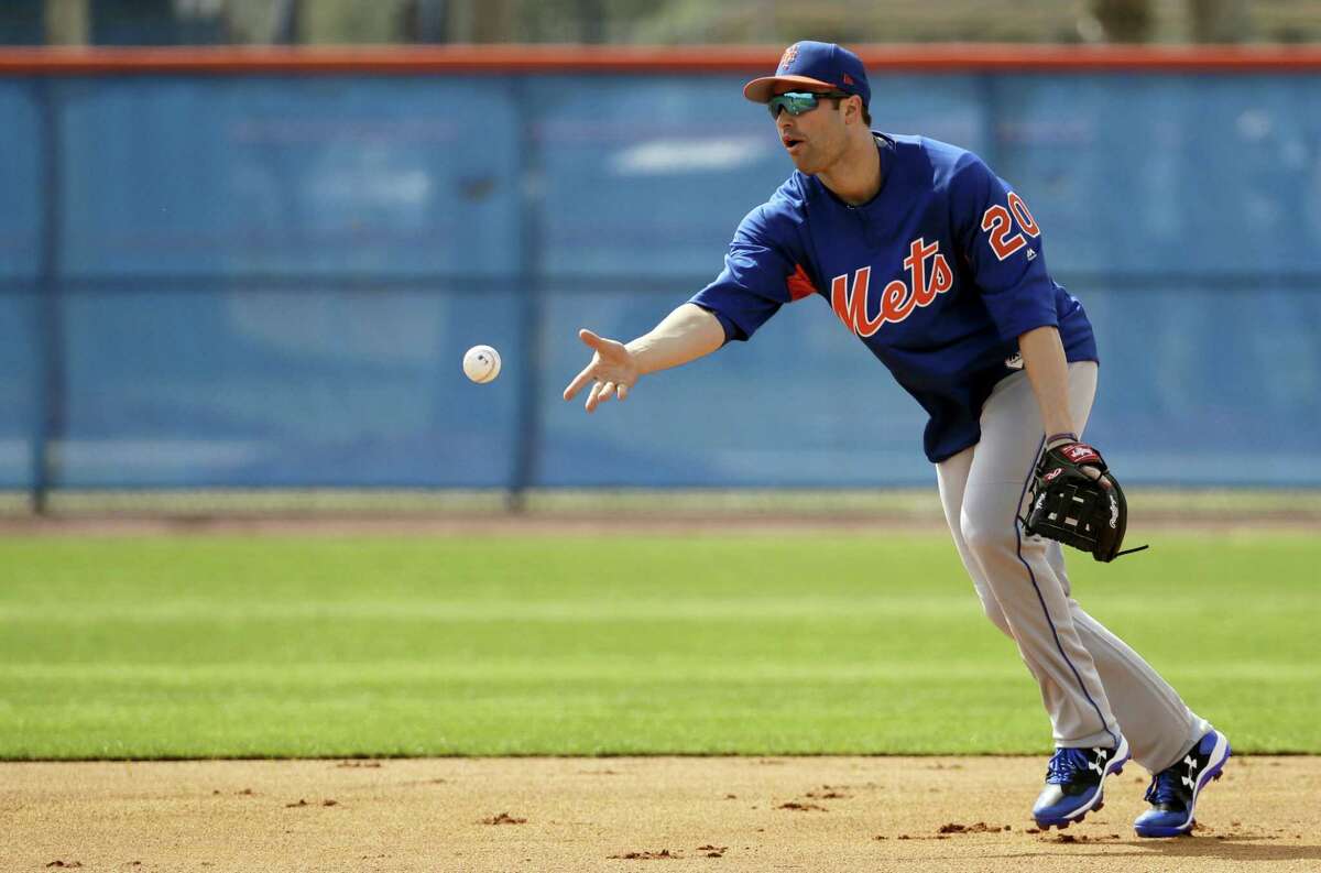New York Mets second baseman Neil Walker tosses the ball to second base during a spring training baseball workout Wednesday in Port St. Lucie, Fla.