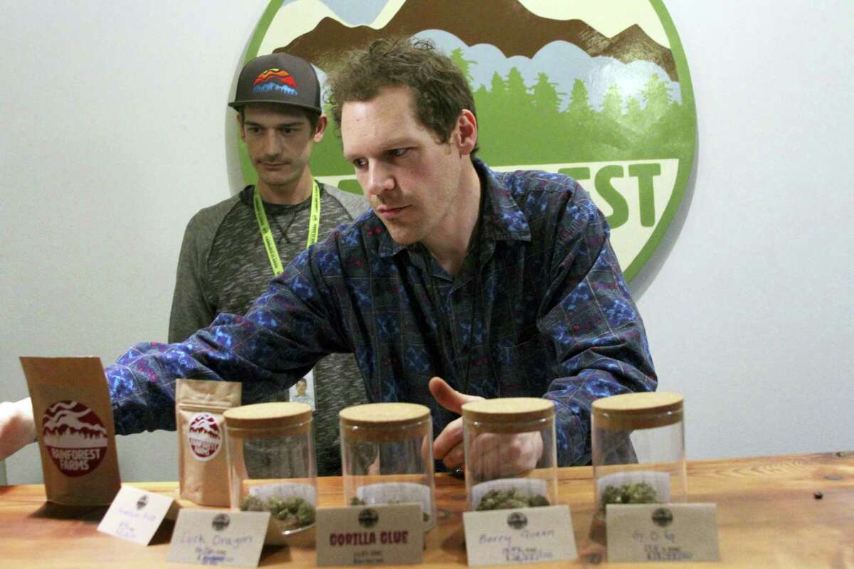 Giono Barrett, right, arranges marijuana products at Rainforest Farms in Juneau, Alaska. James Barrett, left, is co-owner of Juneau’s first marijuana retail store. James and Giono Barrett have a dream: that some of the scores of cruise ship passengers who crowd the streets of the state capital each summer will one day use their shore excursions to kick back and light up a joint in a pot store’s lounge.