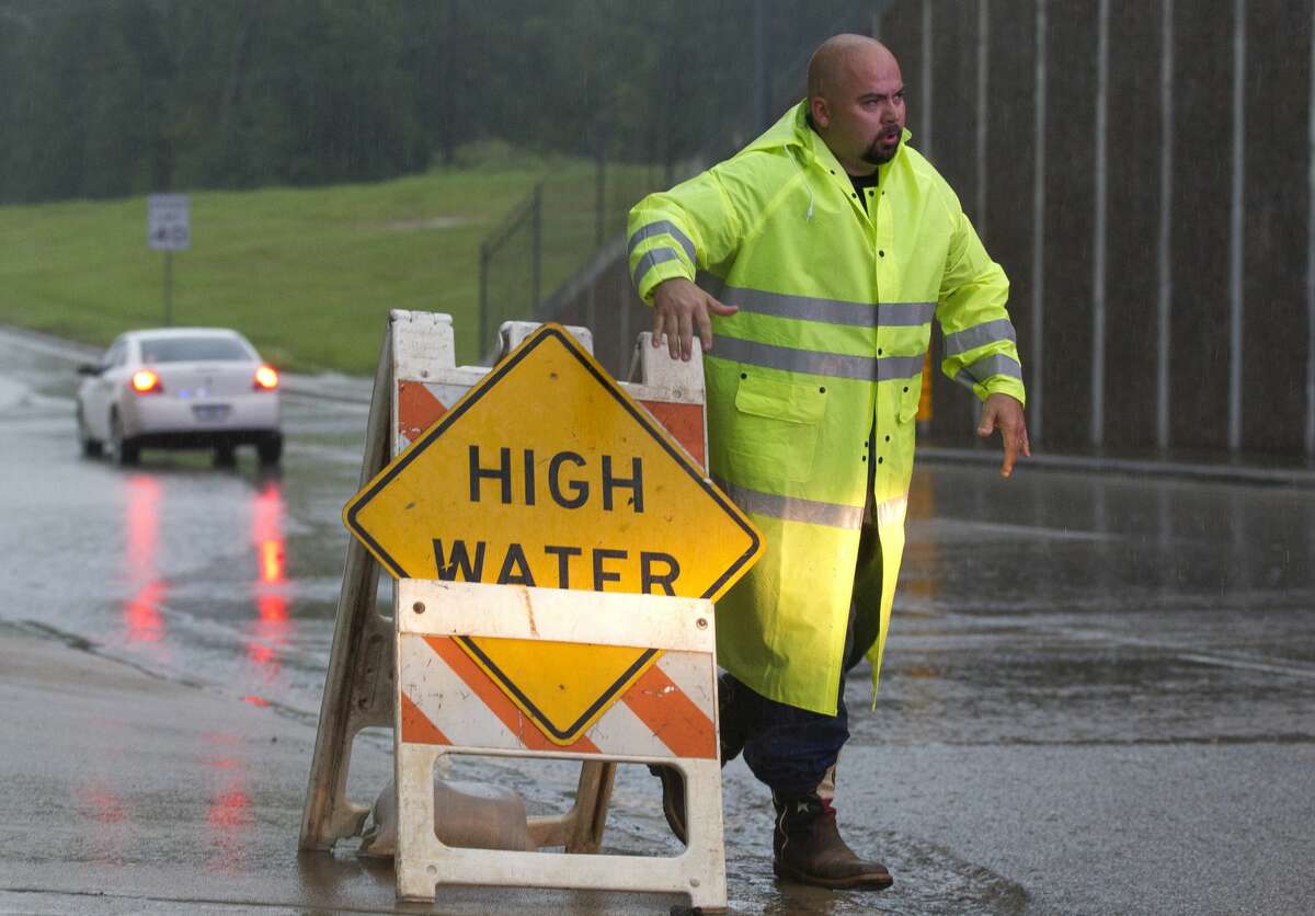 A worker with the City of Conroe Public Works department places a high water sign on the east bound side South Loop 336 near Frazier Street after a woman drove her car through high water, Saturday, Aug. 26, 2017, in Conroe.