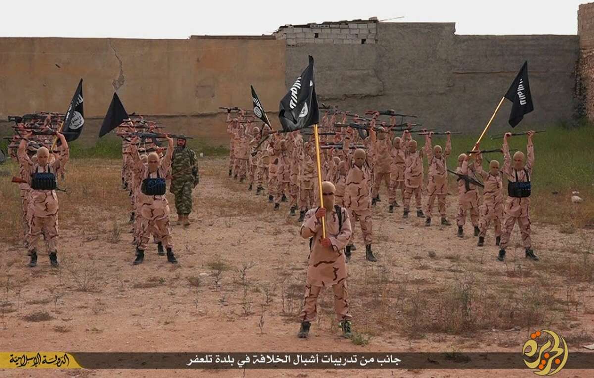 In this photo released on April 25, 2015 by a militant website, which has been verified and is consistent with other AP reporting, young boys known as the “lion cubs” hold rifles and Islamic State group flags as they exercise at a training camp in Tal Afar, near Mosul, northern Iraq. The Iraqi military has announced an agreement Sunday, Sept. 27, 2015 on “security and intelligence cooperation” with Russia, Iran and Syria to help combat the Islamic State group.