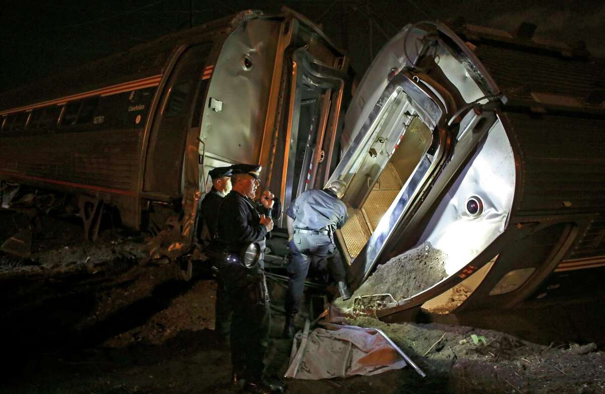 In this May 12, 2015 photo, emergency personnel work the scene of a train wreck An Amtrak train headed to New York City derailed and crashed in Philadelphia. Amtrak says it will install video cameras inside locomotive cabs that record the actions of train engineers.