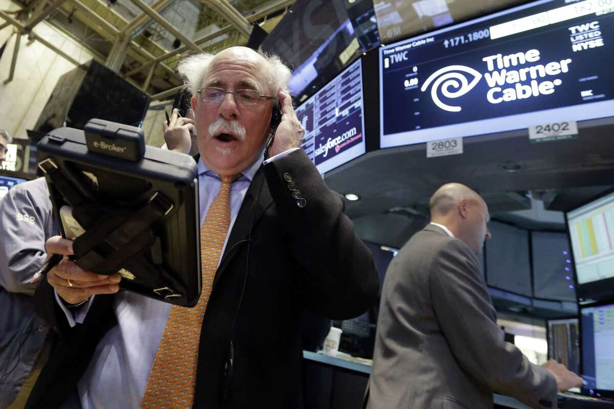 Trader Peter Tuchman, left, works the post that handles Time Warner Cable on the floor of the New York Stock Exchange Tuesday.