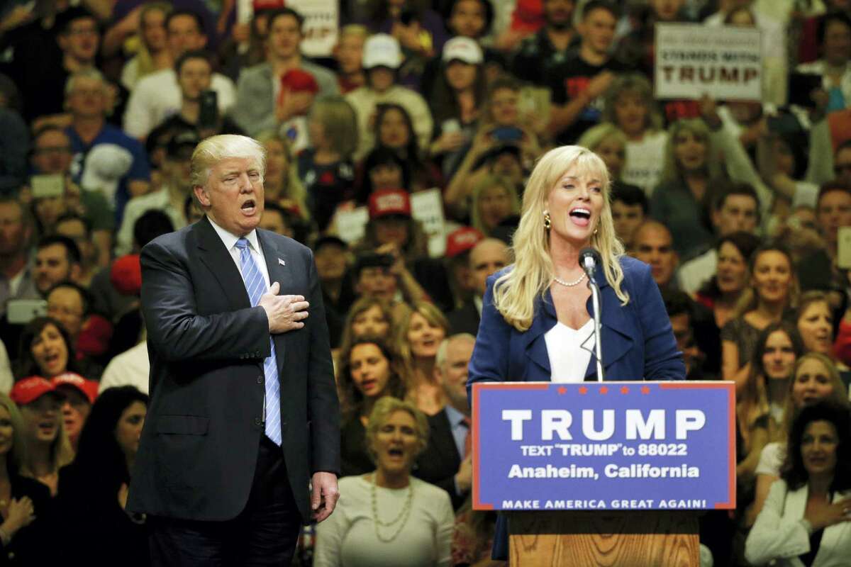 Republican presidential candidate Donald Trump, left, sings the National Anthem with unidentified woman during a rally at the Anaheim Convention Center, Wednesday, May 25, 2016, in Anaheim, Calif.
