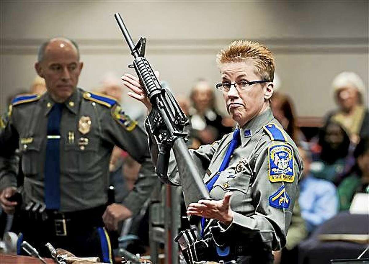 In this Jan. 28, 2013 photo, firearms training unit Detective Barbara J. Mattson, of the Connecticut State Police, holds up a Bushmaster AR-15 rifle, the same make and model of gun used by Adam Lanza in the Sandy Hook School shooting, for a demonstration during a hearing of a legislative subcommittee reviewing gun laws, at the Legislative Office Building in Hartford, Conn. The families of nine of the 26 people killed and a teacher injured on Dec. 14, 2012, at the Sandy Hook Elementary School filed a lawsuit against the manufacturer, distributor and seller of the Bushmaster AR-15 rifle used by Lanza in the shooting.
