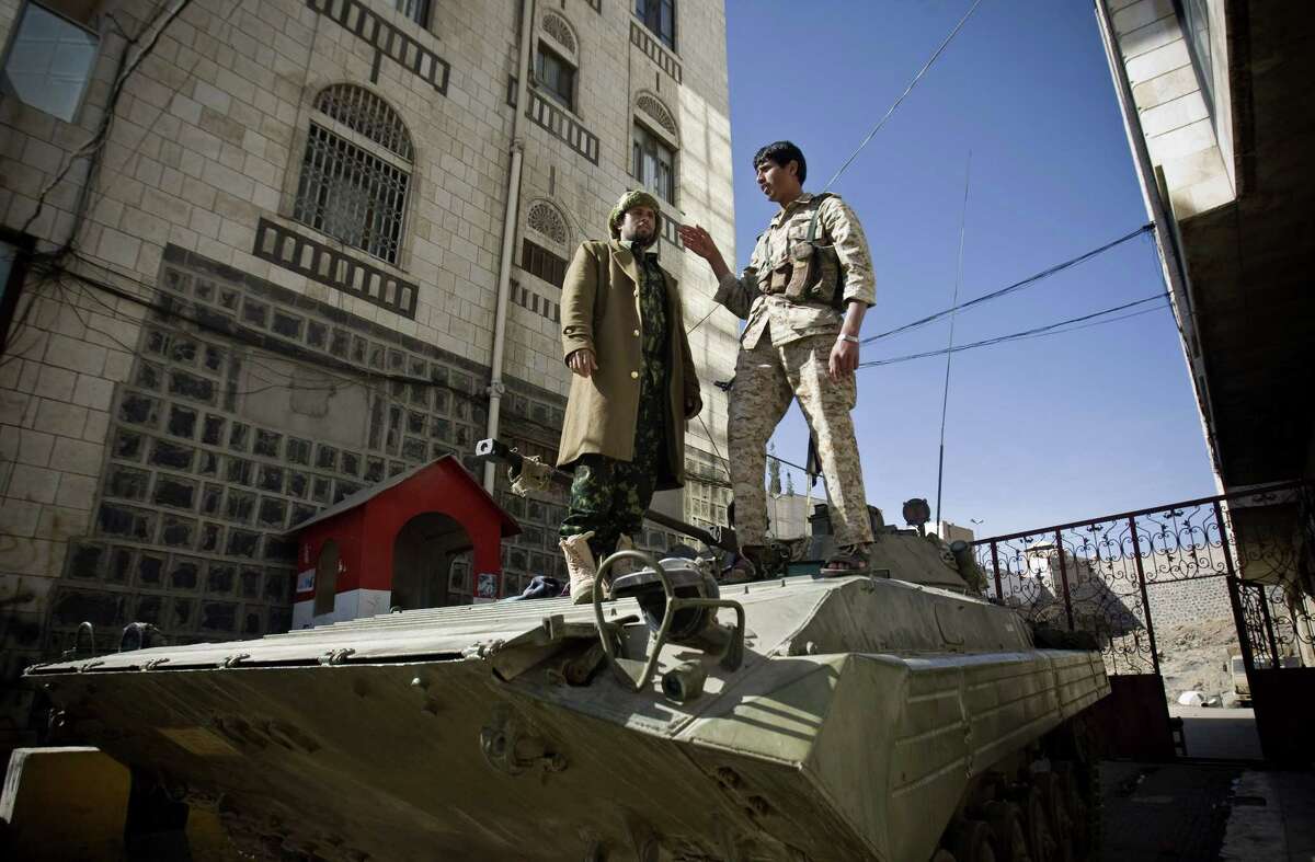 Houthi Shiite Yemeni wearing army uniforms stand atop an armored vehicle, which was seized from the army during recent clashes, outside the house of Yemen's President Abed Rabbo Mansour Hadi in Sanaa, Yemen, Thursday, Jan. 22, 2015. Heavily armed Shiite rebels remain stationed outside the Yemeni president's house and the palace in Sanaa, despite a deal calling for their immediate withdrawal to end a violent standoff. (AP Photo/Hani Mohammed)