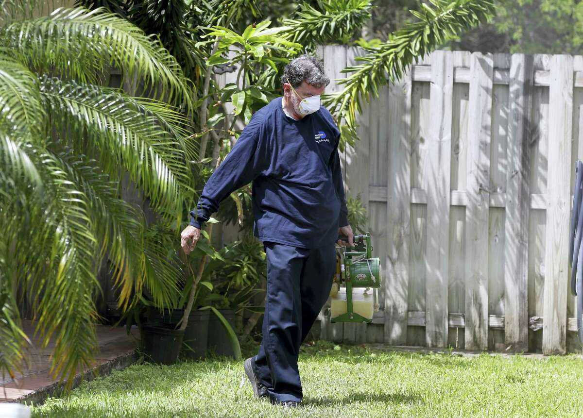 In this photo taken April 12, 2016, Giraldo Carratala, an inspector with the Miami- Dade County, Fla. mosquito control unit, sprays pesticide in the yard of a home in Miami, Fla.