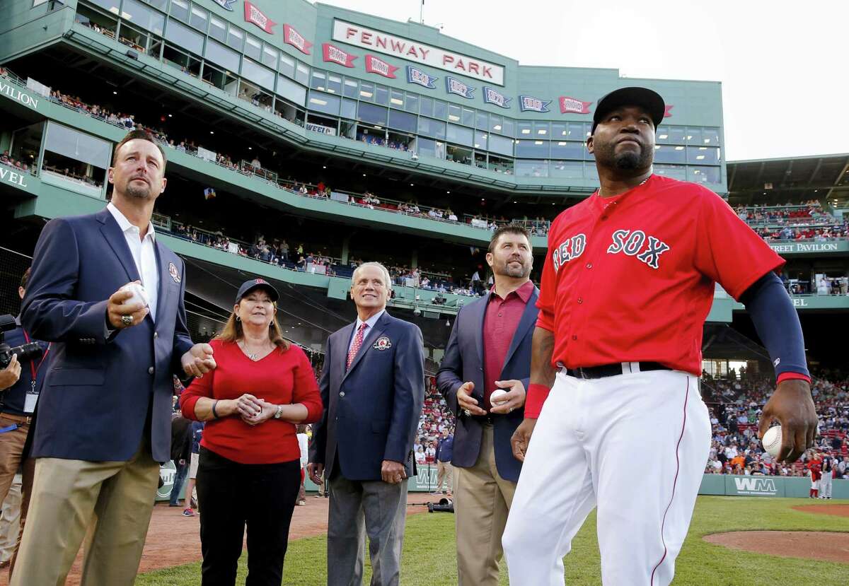 Former Red Sox players, Tim Wakefield, left, and Jason Varitek second from right, former Red Sox president Larry Lucchino, center, Tami Garvin, second from left, granddaughter of former Red Sox Ira Flagstead and David Ortiz, right, stand on the field during Red Sox Hall of Fame induction ceremonies on Friday.