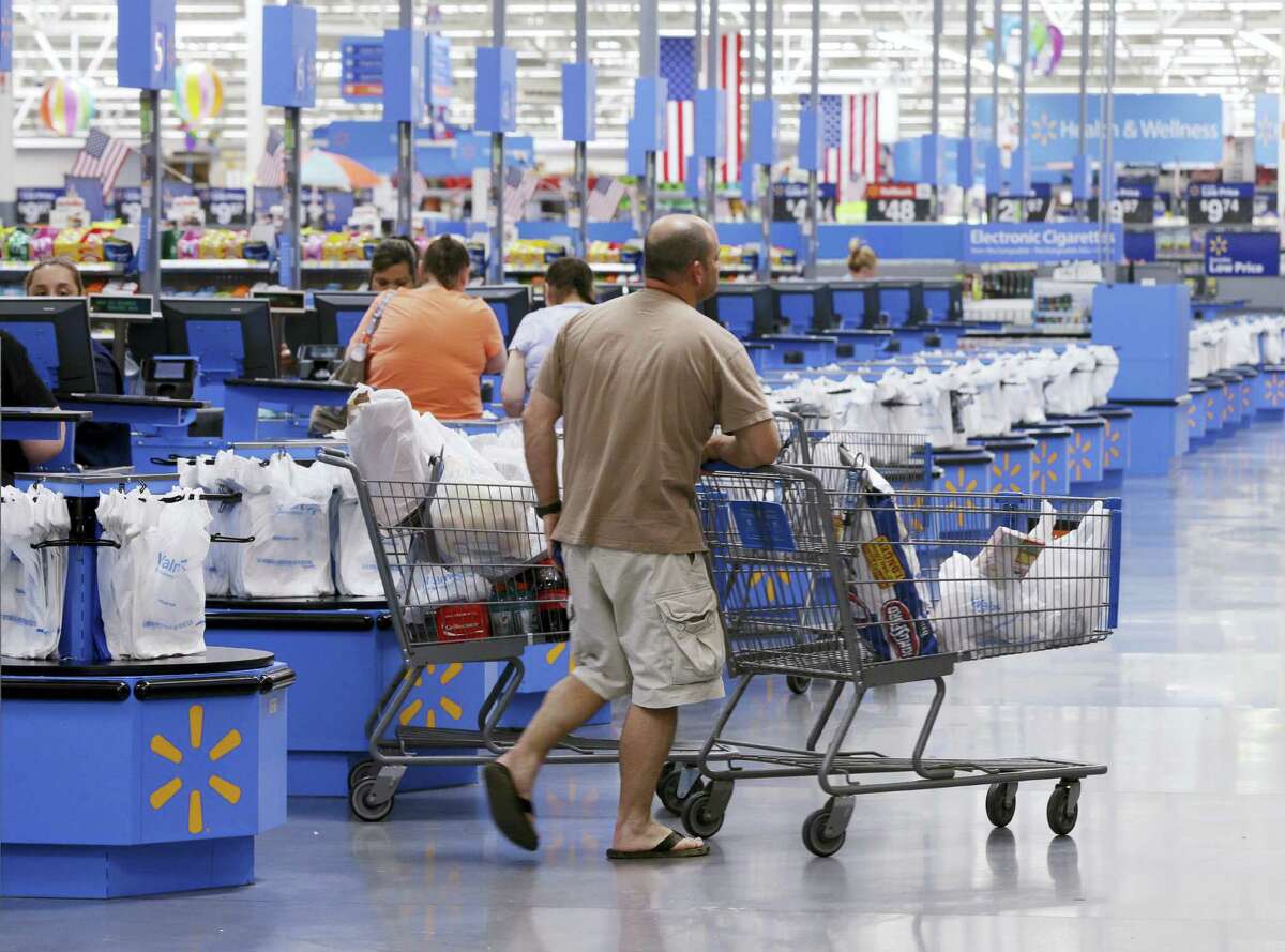 In this Thursday, June 4, 2015, photo, shoppers walk from the checkout at a Wal-Mart Supercenter store in Springdale, Ark. Wal-Mart announced Friday, Jan. 15, 2016, that it is closing 269 stores, more than half of them in the U.S. and another big chunk in its challenging Brazilian market. The store closures will start at the end of January.