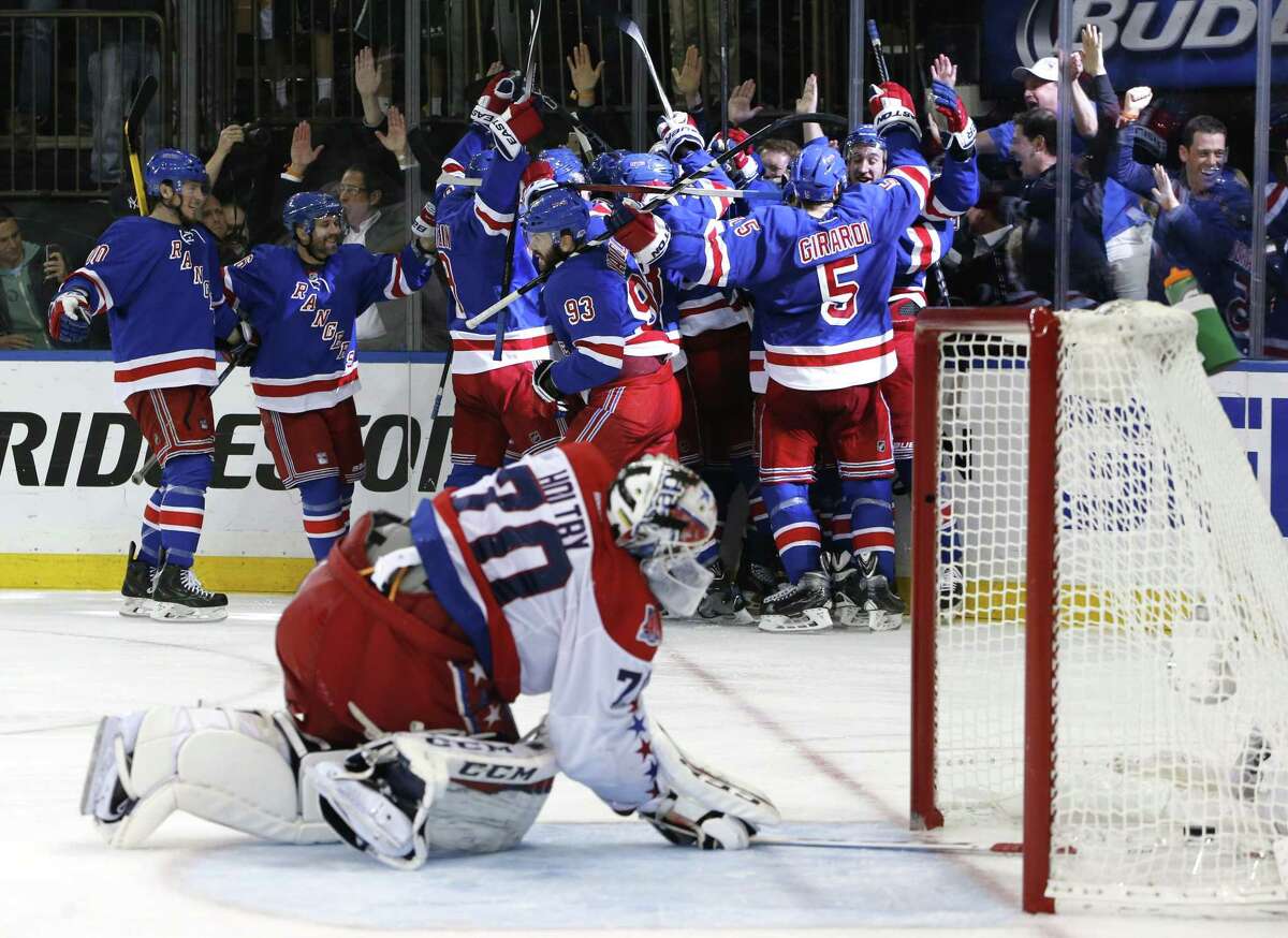 The New York Rangers celebrate the game-winning goal by center Derek Stepan against the Washington Capitals on Wednesday as Capitals goalie Braden Holtby looks at the puck in the net.