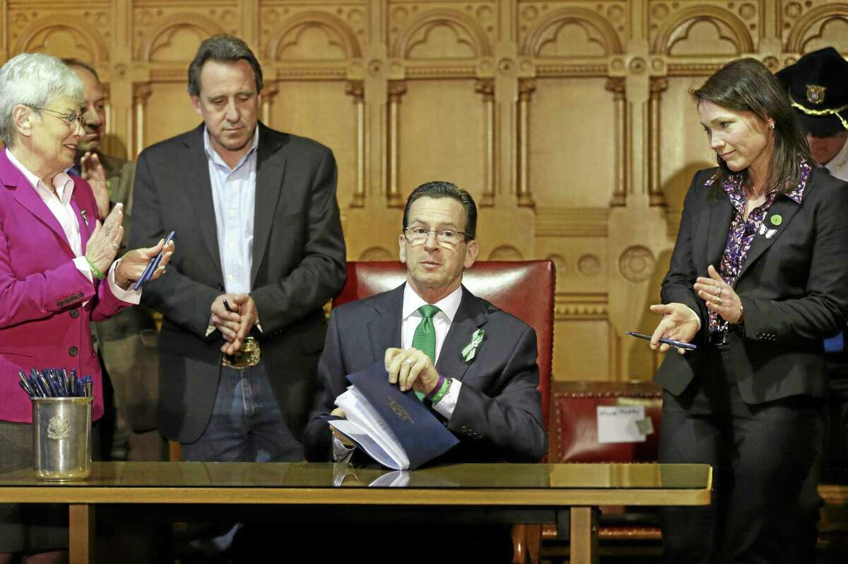 Connecticut Gov. Dannel P. Malloy, center, completes signing legislation that includes new restrictions on weapons and large capacity ammunition magazines, at the Capitol in Hartford, Conn., Thursday, April 4, 2013.
